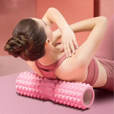Woman using a pink foam roller on a pink surface